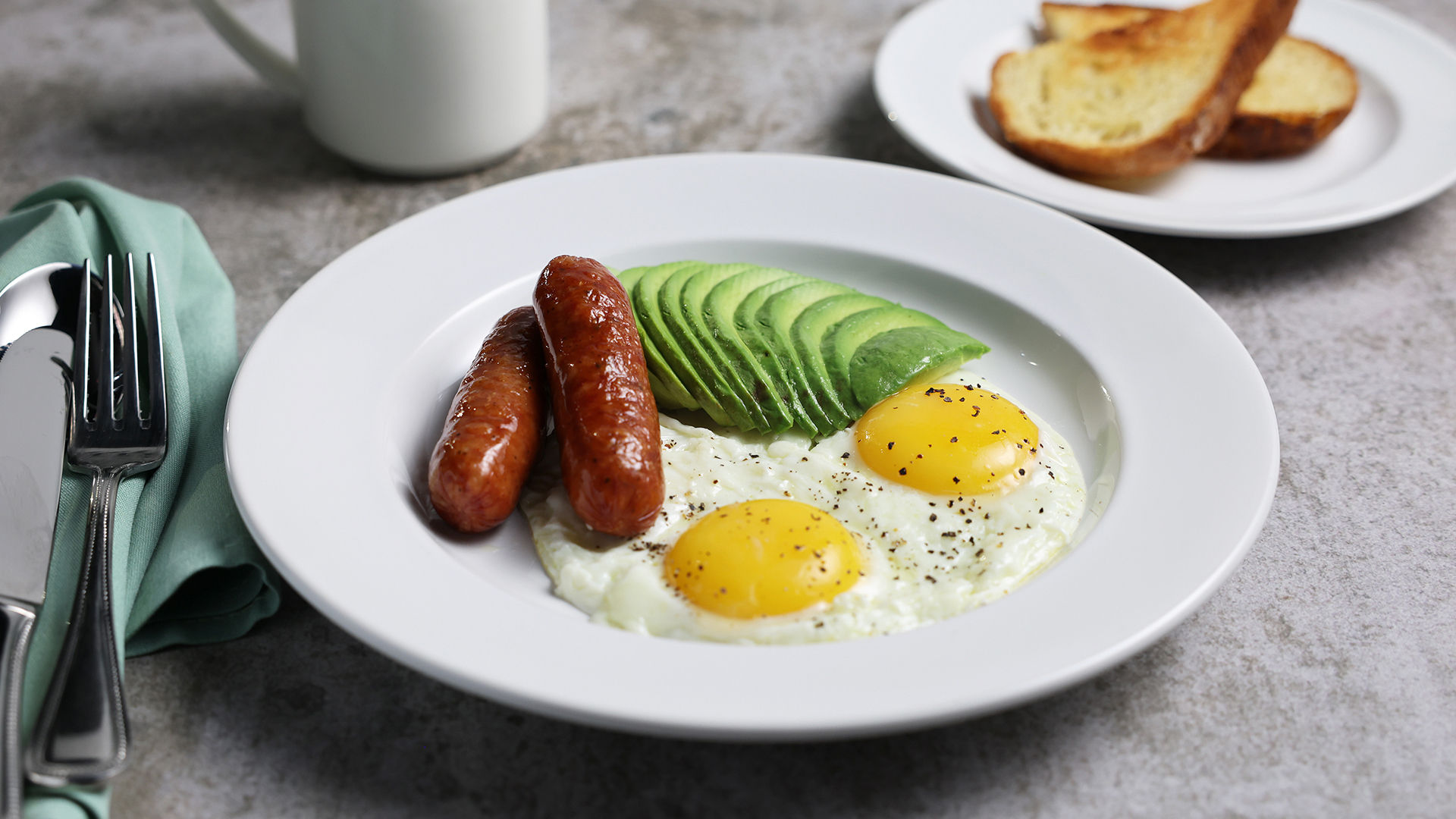 Eggs, sausage and avocado in a bowl, with toast and coffee