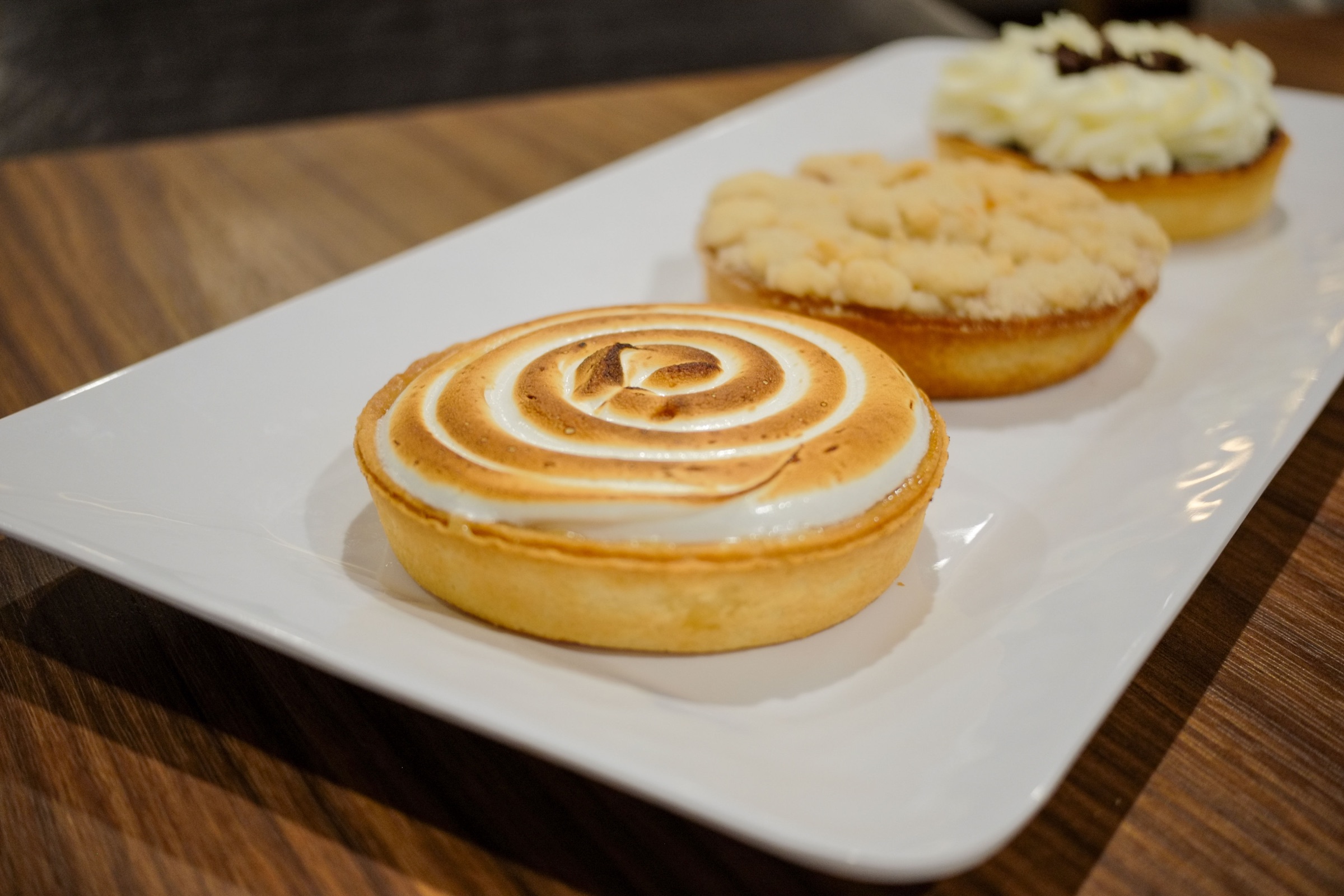 Three dessert tarts on a white plate