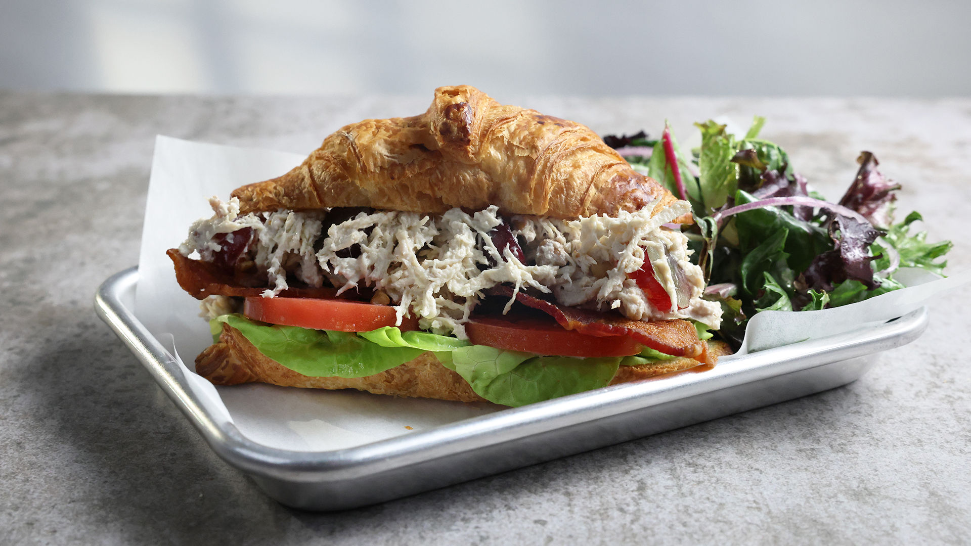 Chicken salad croissant with bacon, tomato, lettuce and a side salad