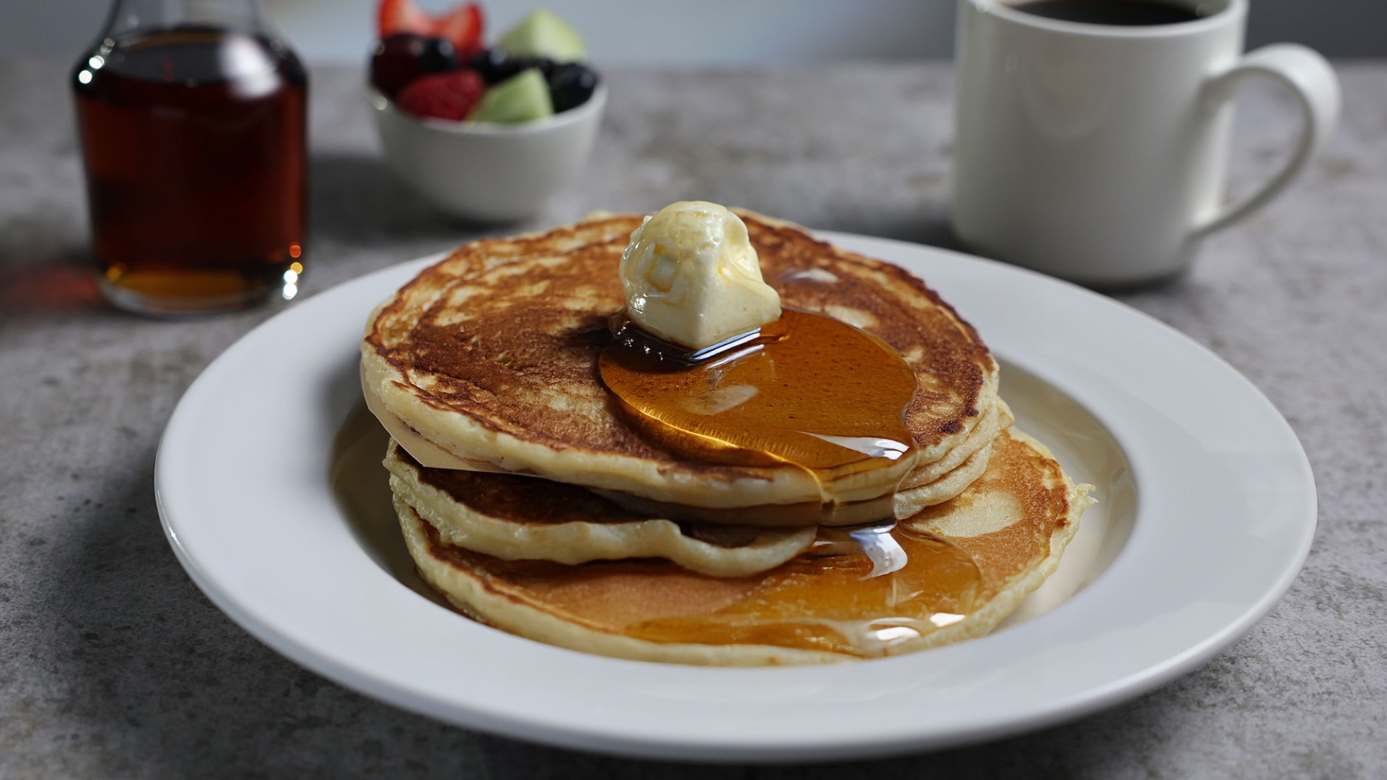 A stack of pancakes with melting butter and maple syrup