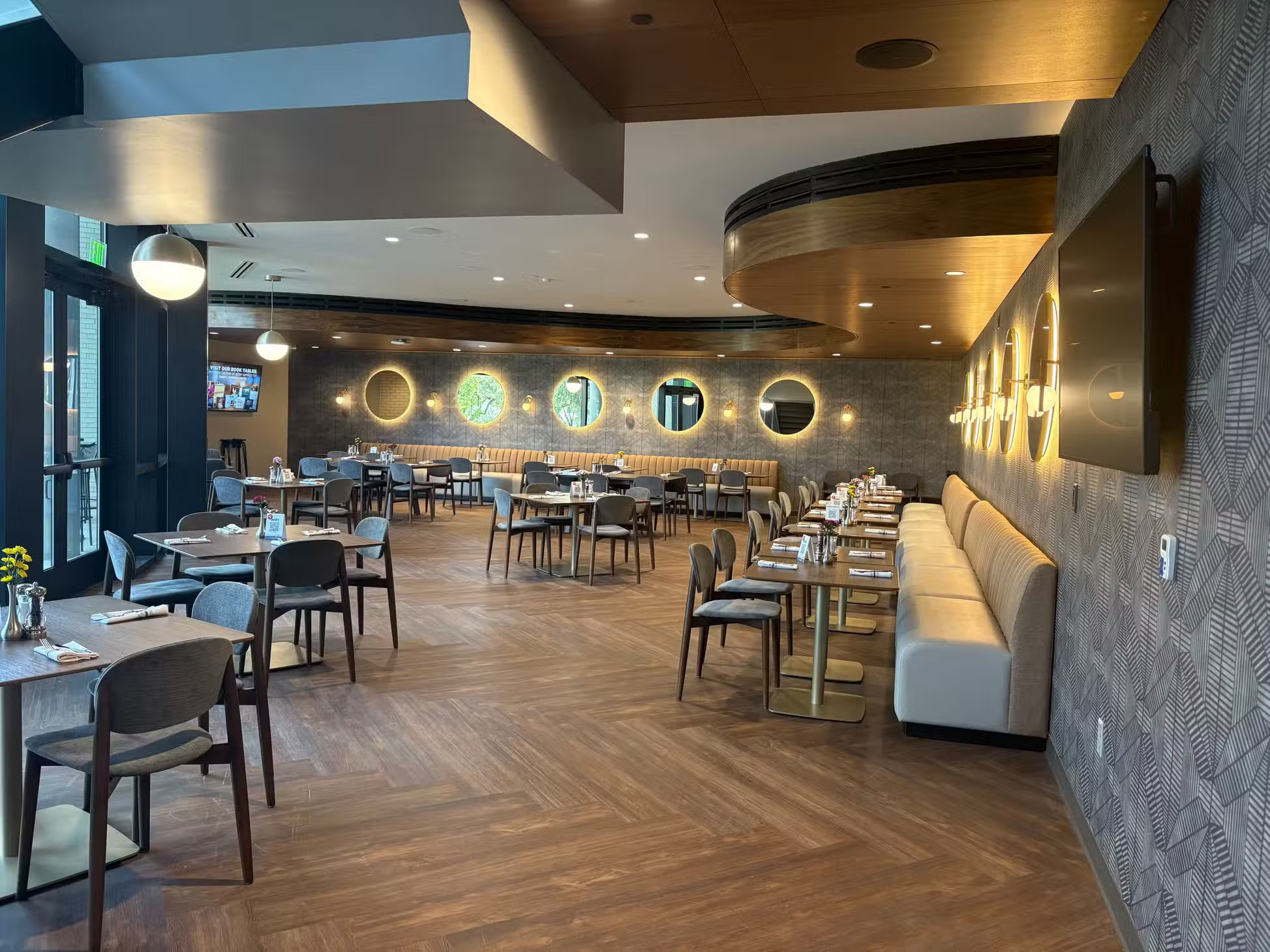 The café dining room with tables set, banquet seating, and warm wall lights